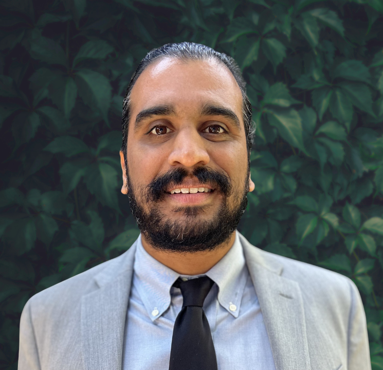 Headshot of Ameil Kenkare with a dark green leaf background.