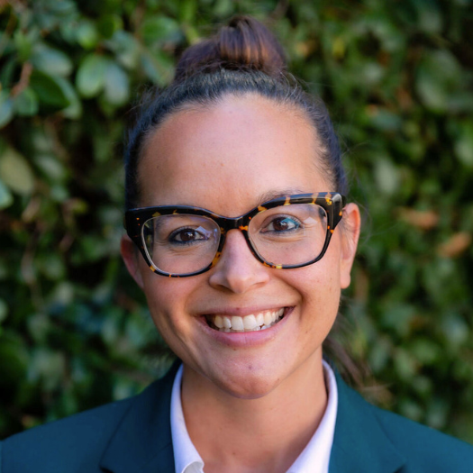 Headshot of Meghan Gordon in front of dark green leaves.